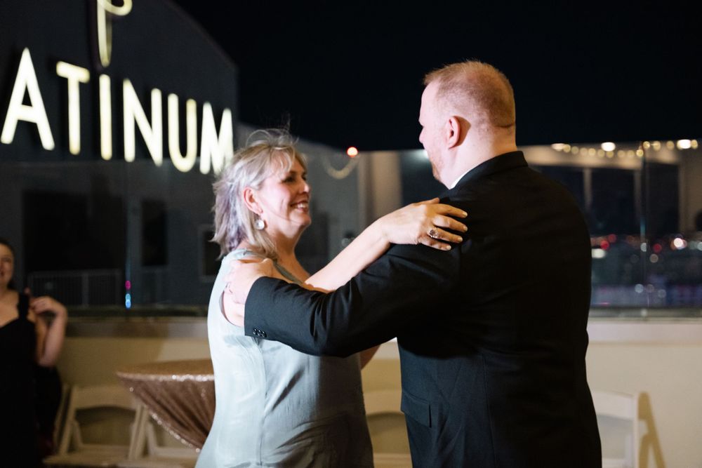 Couple dancing together at night on a rooftop venue with illuminated PLATINUM sign in the background.