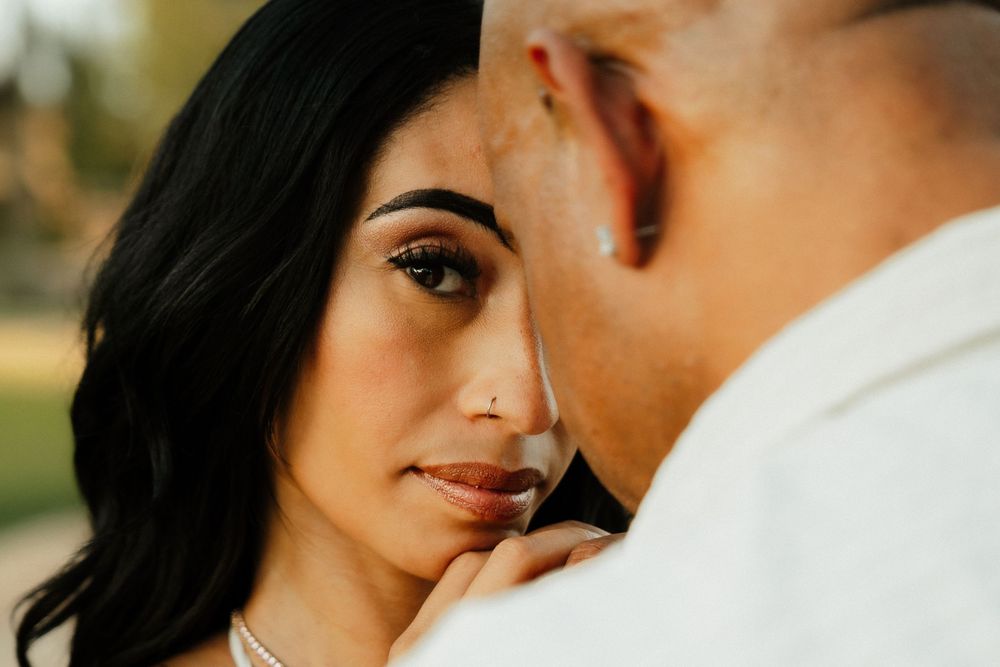 Close-up of a woman gazing lovingly at a man during a romantic outdoor engagement photo session.