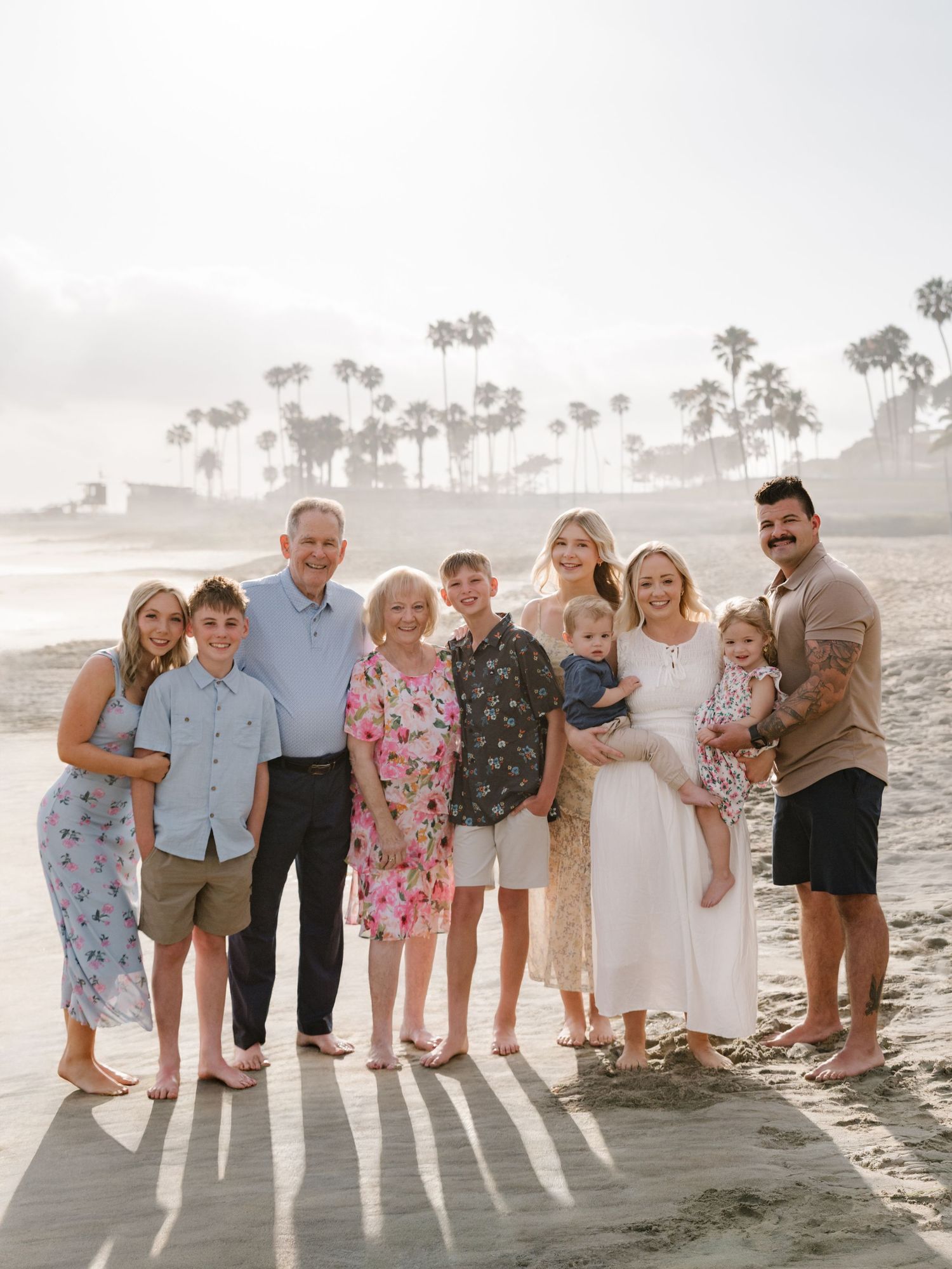 Multigenerational family group standing together on the beach during a Newport Beach extended family photography session.