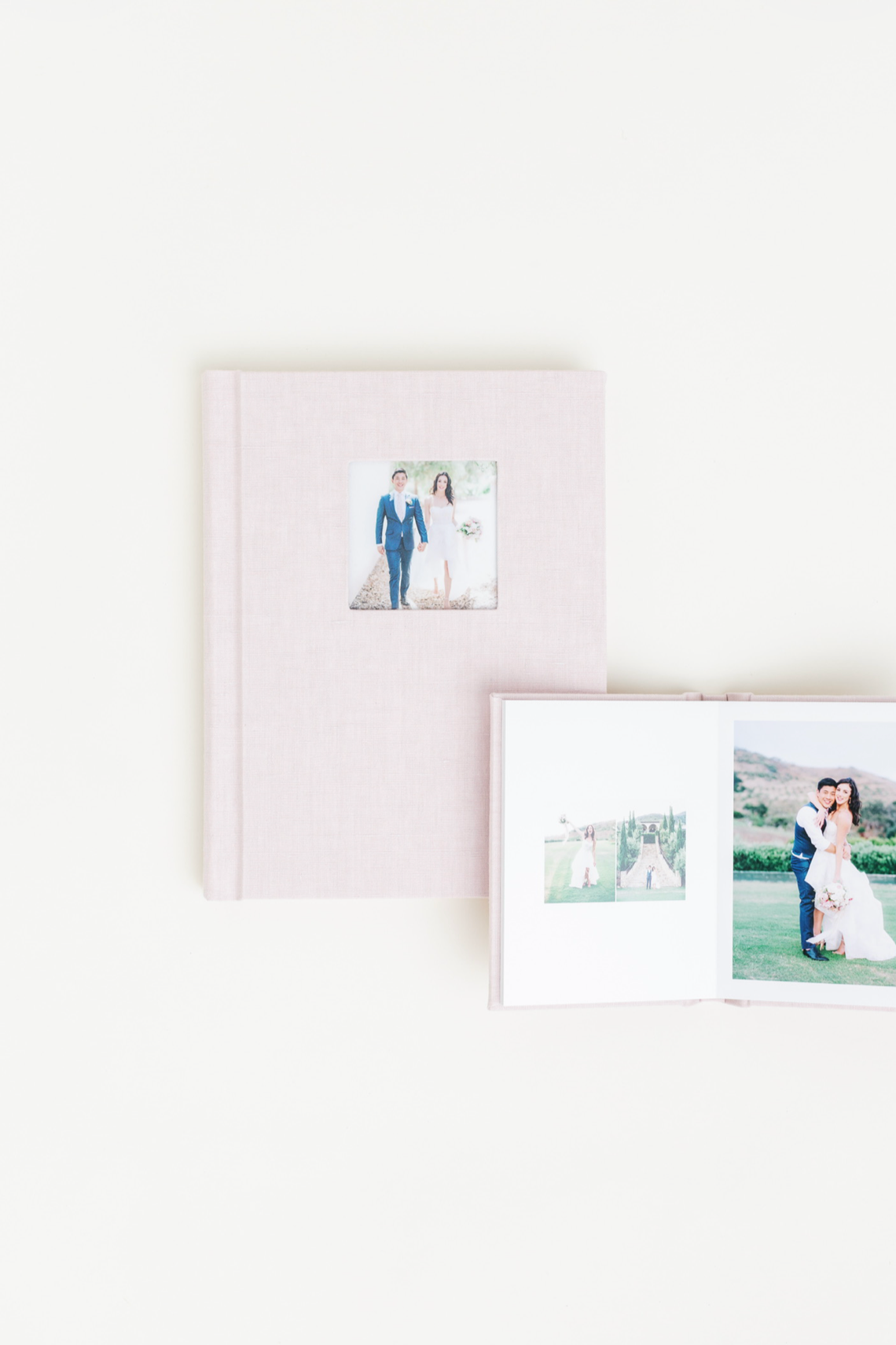Two elegant wedding photo albums with linen covers displaying couple portraits on a white background.