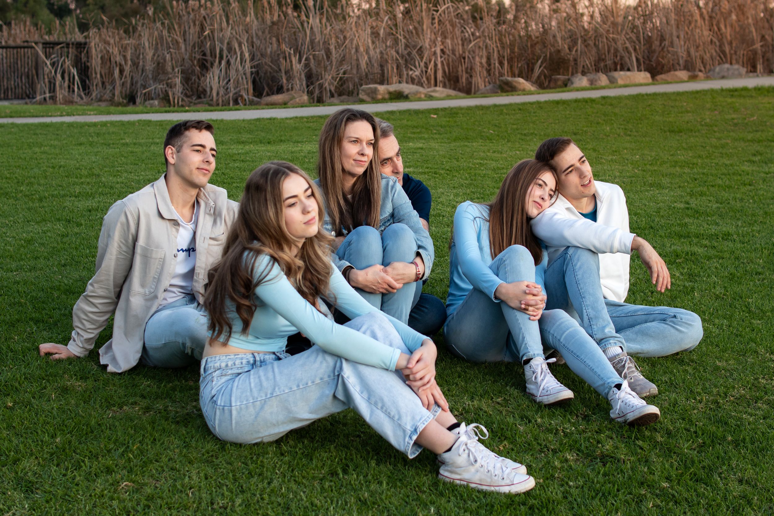 A family sitting together on a hilltop at sunset overlooking Rouse Hill, Beaumont Hills