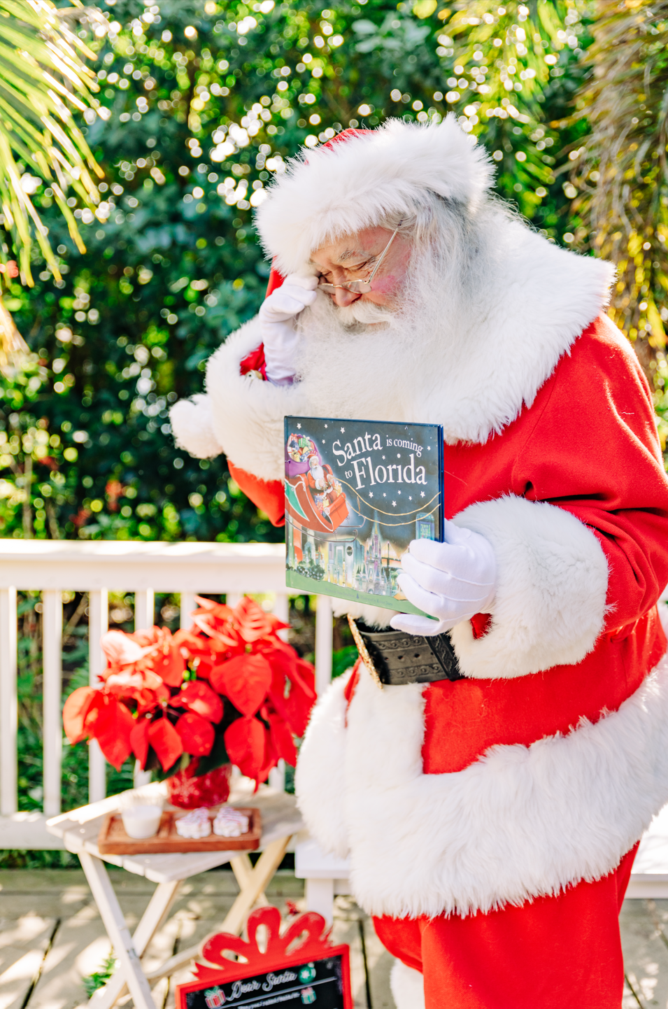 Santa Claus reading a Florida Christmas book during a Santa photo experience in Lake Worth Beach.