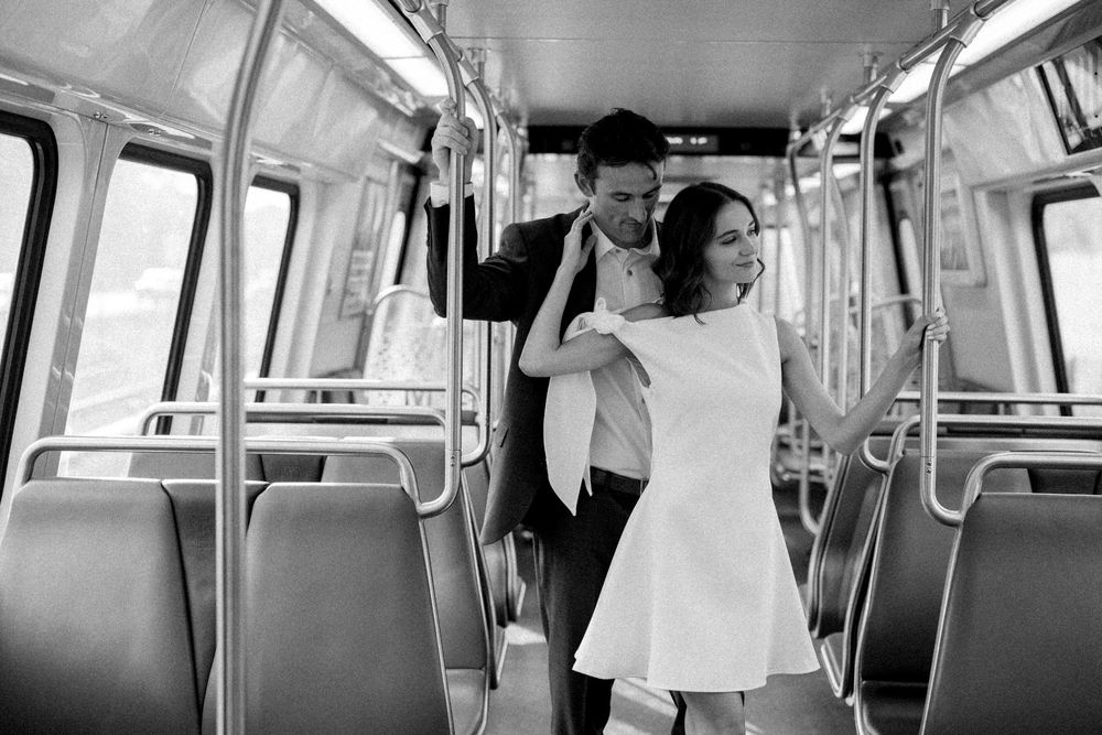 Black and white photo of a couple embracing romantically inside an empty subway train car.