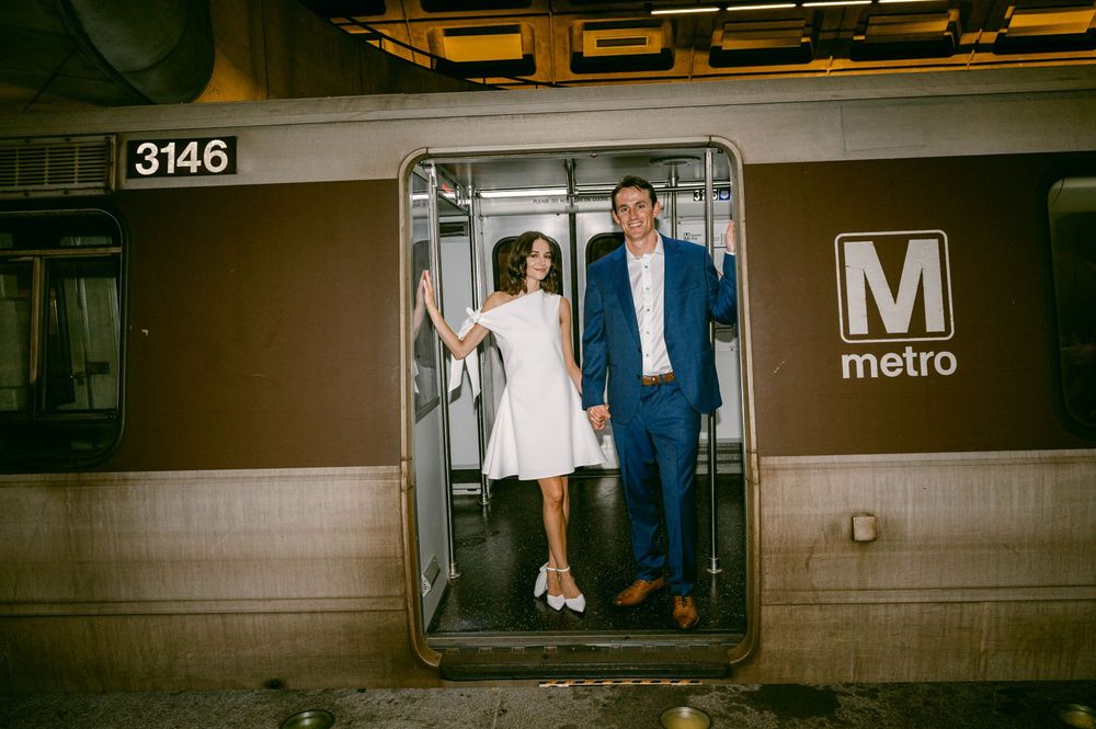 Couple in wedding attire posing in open Metro train car doorway, car number 3146, smiling and holding hands.