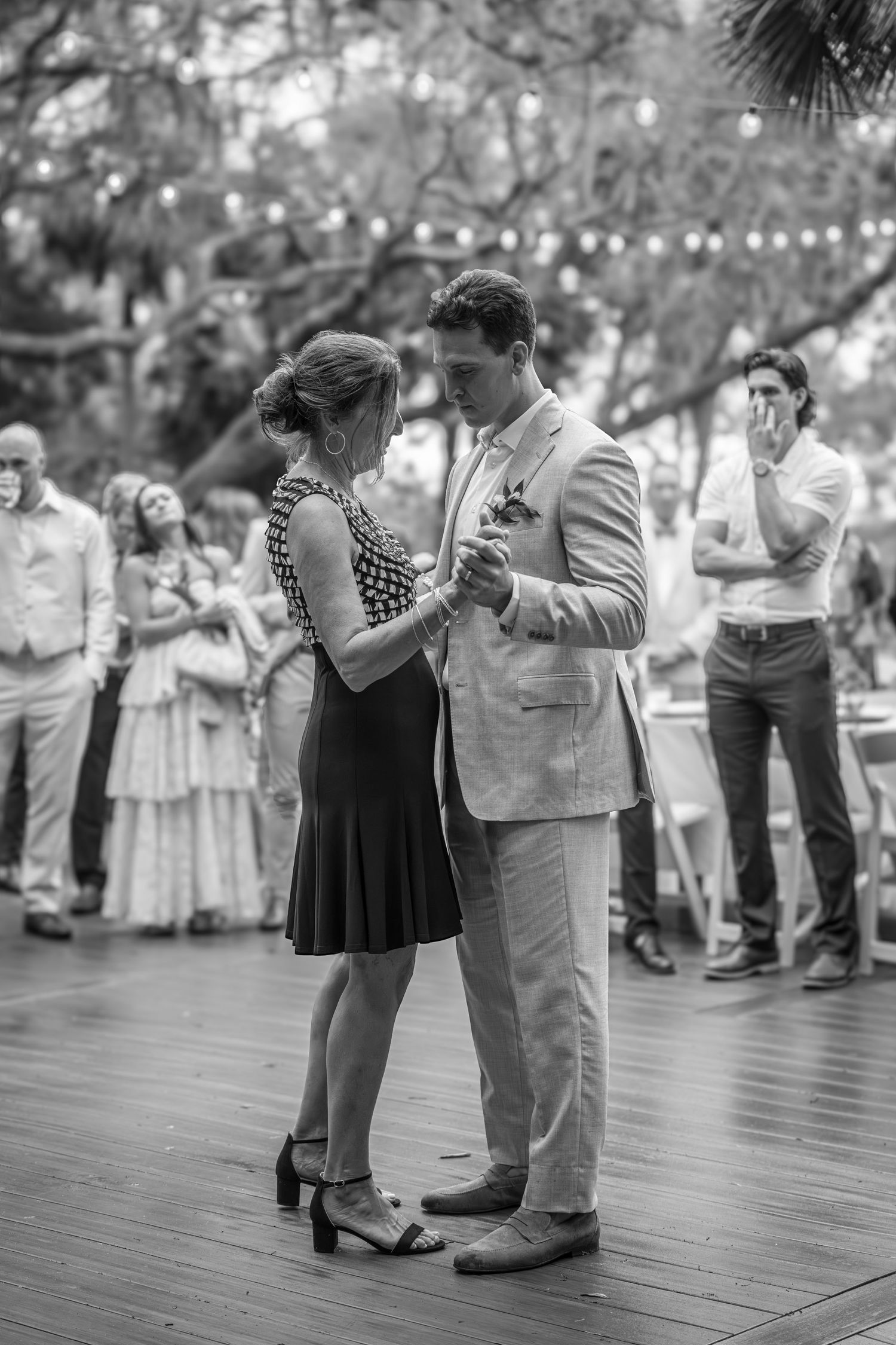 Black and white photo of a couple sharing their first dance at an outdoor wedding reception.