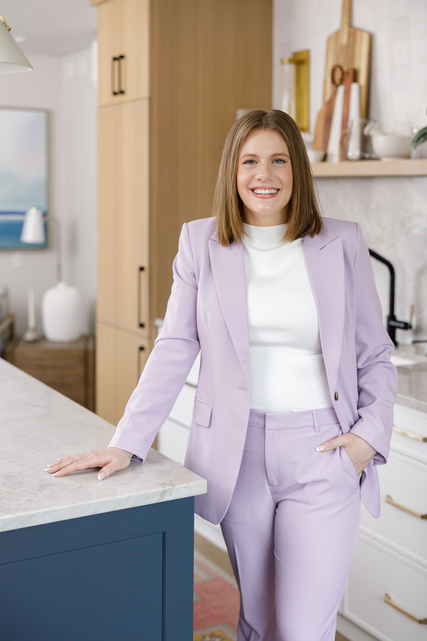 female real estate agent lifestyle headshot in Auburn, WA standing in kitchen hand on counter in purple suit