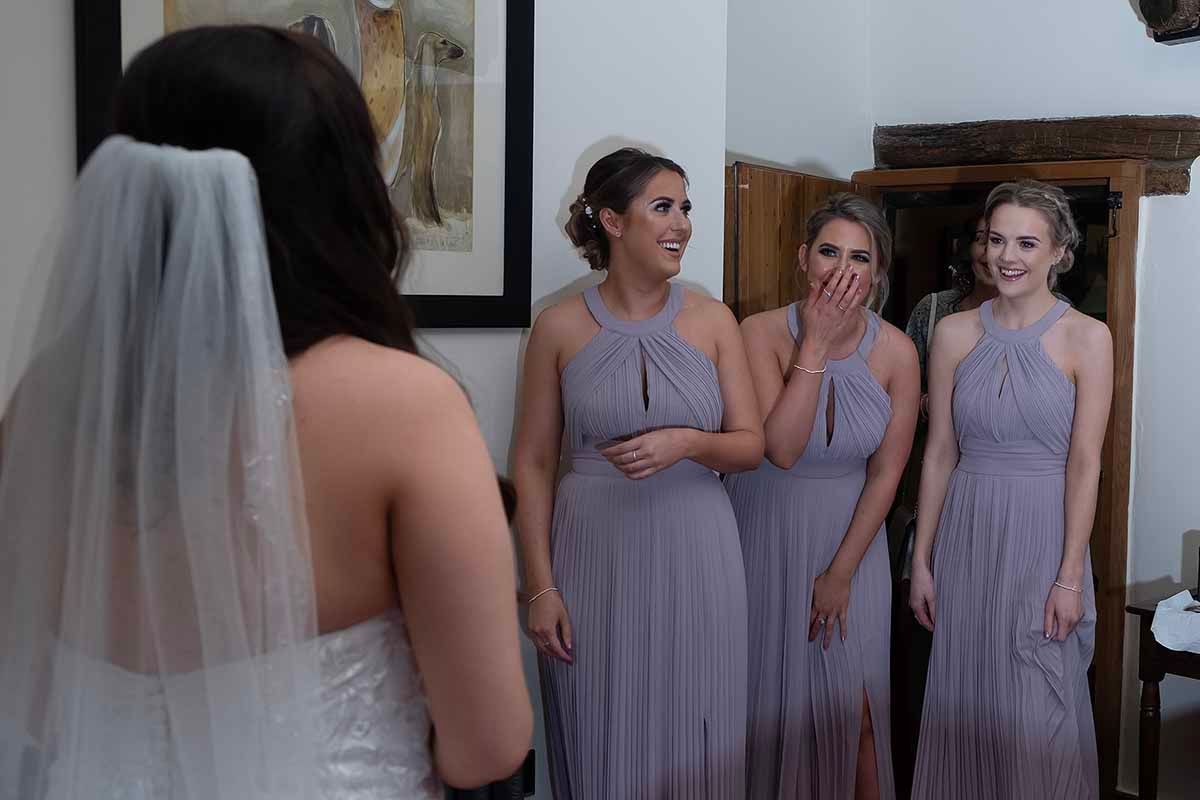 Bridesmaids in lavender gowns react emotionally seeing bride in the reveal moment at New House Farm Cockermouth
