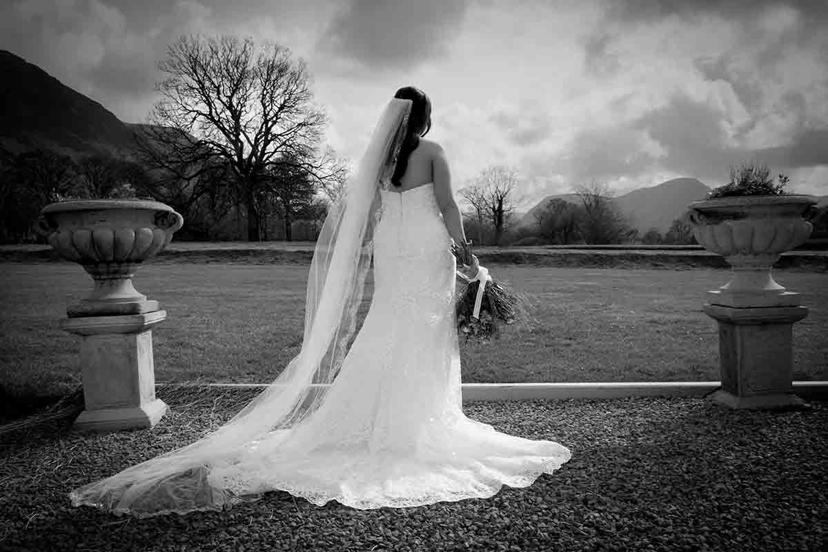 Bride looking down Lorton Valley from New House Farm Cockermouth whilst standing in the garden with mountains in the background.