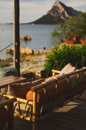 Rustic wooden bench on a seaside terrace with a stunning mountain and ocean view at golden hour.