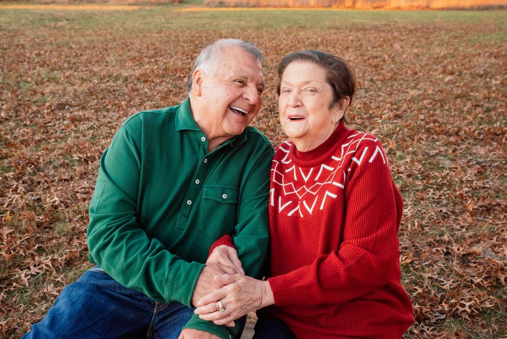 Happy elderly couple laughing together outdoors in an autumn field.