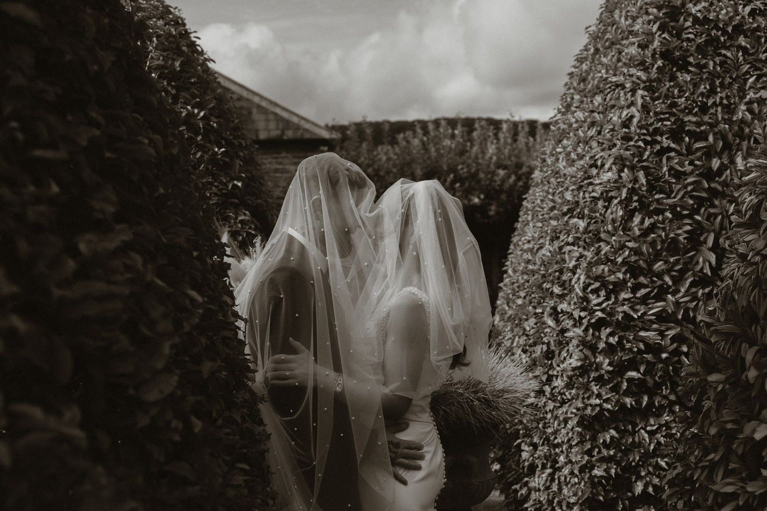 Bride and groom beneath a veil in the gardens at Tankardstown House.