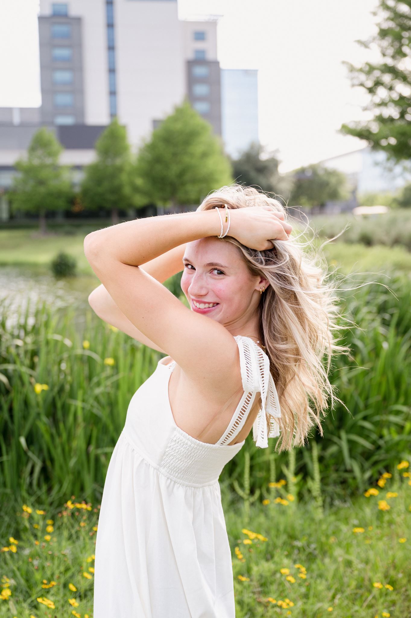 Blonde high school girl wearing a white dress in a field of green foliage in Spring, tx.