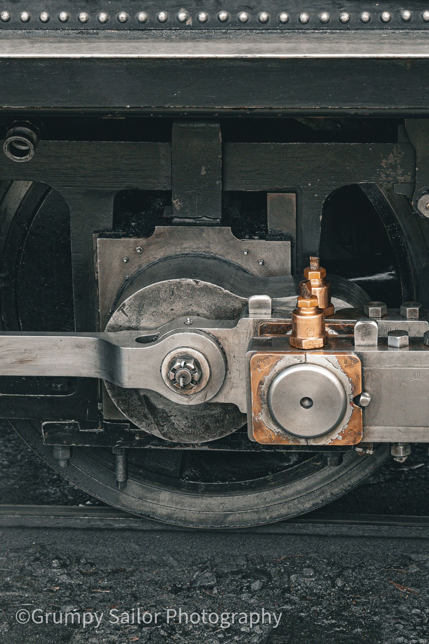Close-up of a vintage steam locomotive wheel and brass mechanical components on a heritage railway engine.