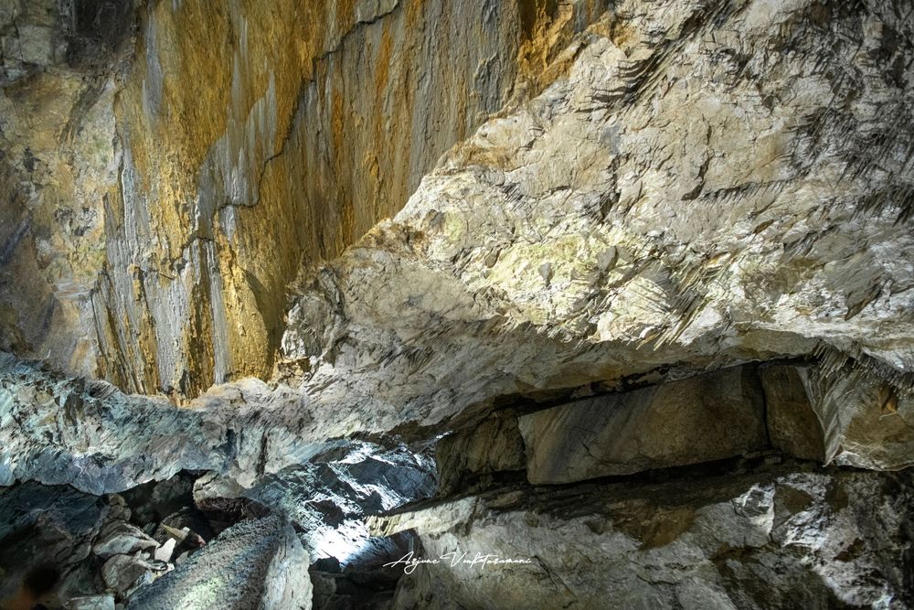 Dramatic cave interior with layered rock formations in golden and white hues, showcasing natural geological beauty.
