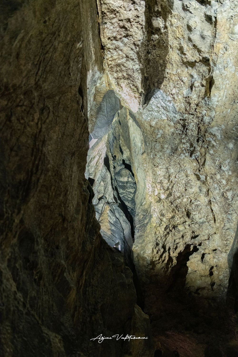 Narrow rocky cave passage with dramatic limestone walls and dark crevice in natural cavern formation.