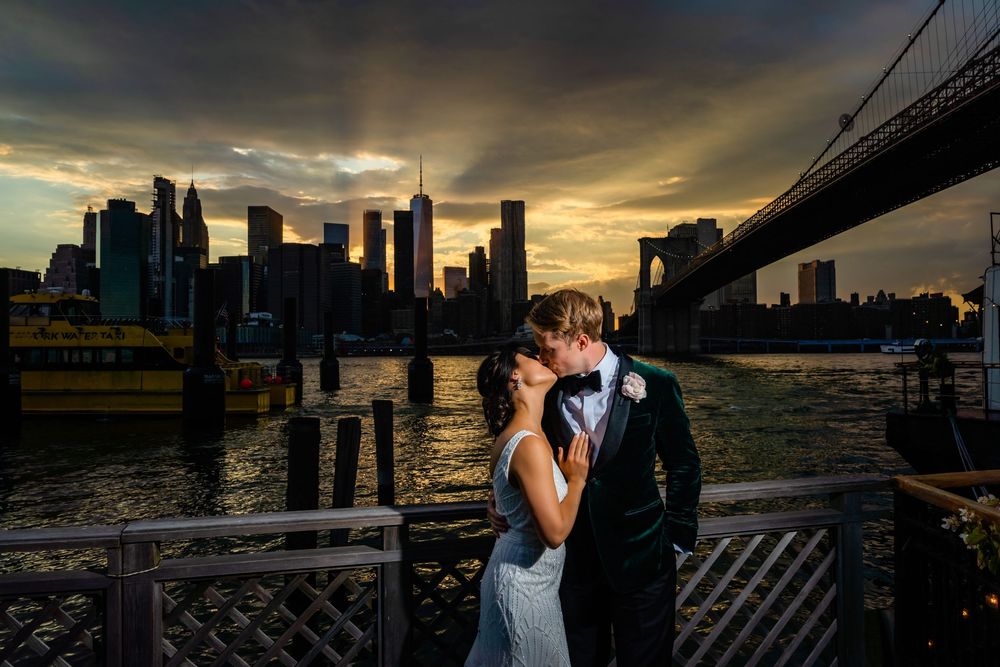 Couple kiss on a Brooklyn pier at sunset with the Brooklyn Bridge and Manhattan skyline behind, River Cafe wedding