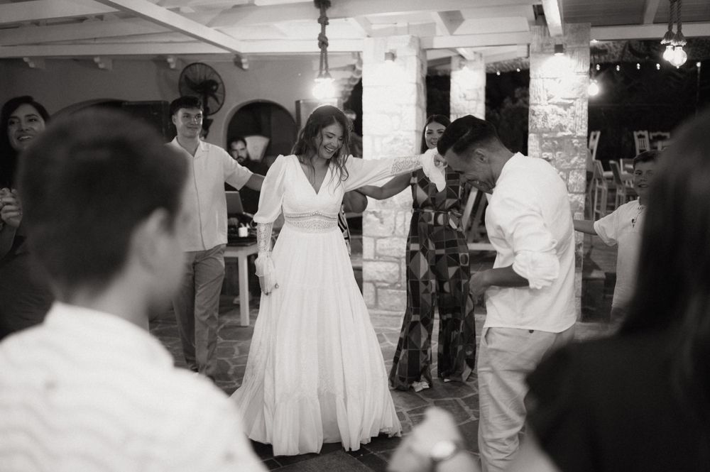 Black and white photo of a bride in a white gown dancing with a guest at an elegant wedding reception.