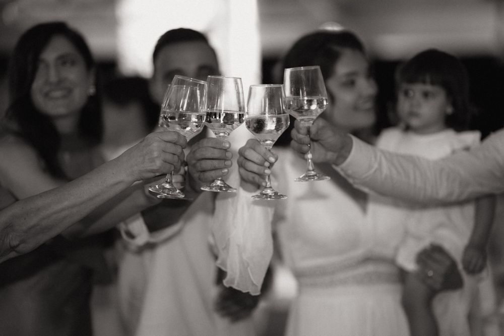 Black and white photo of people clinking wine glasses in a celebratory toast at a wedding reception.