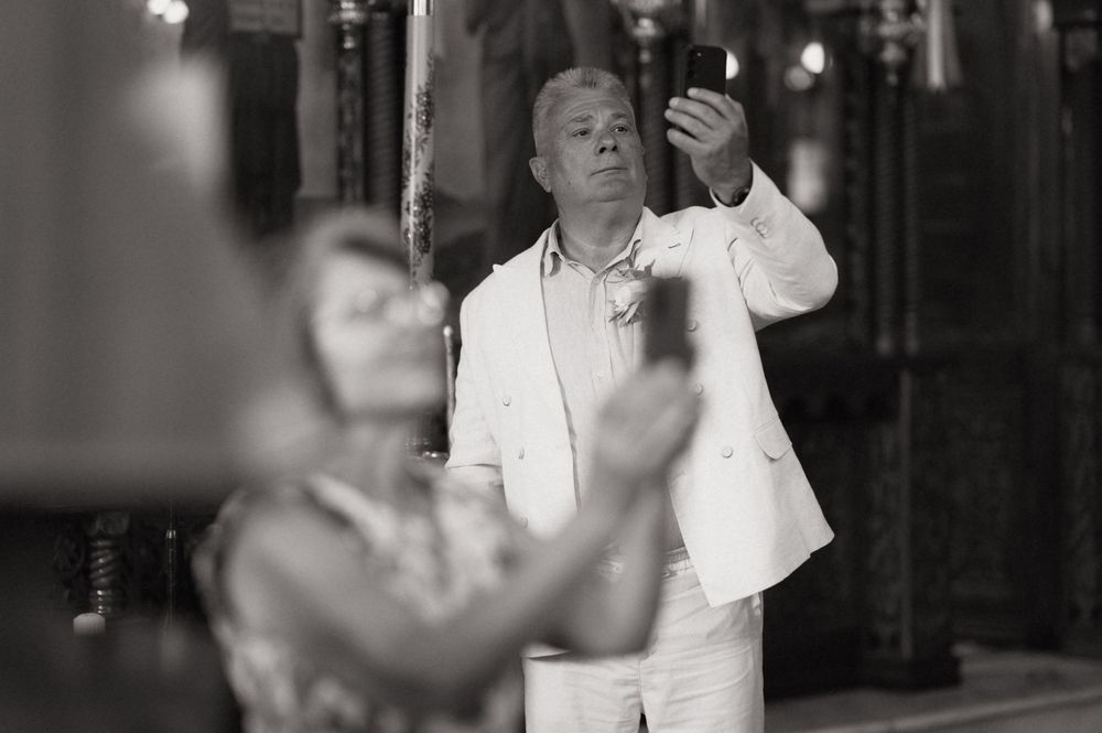 Black and white photo of a man in white suit holding a candle during a religious ceremony.