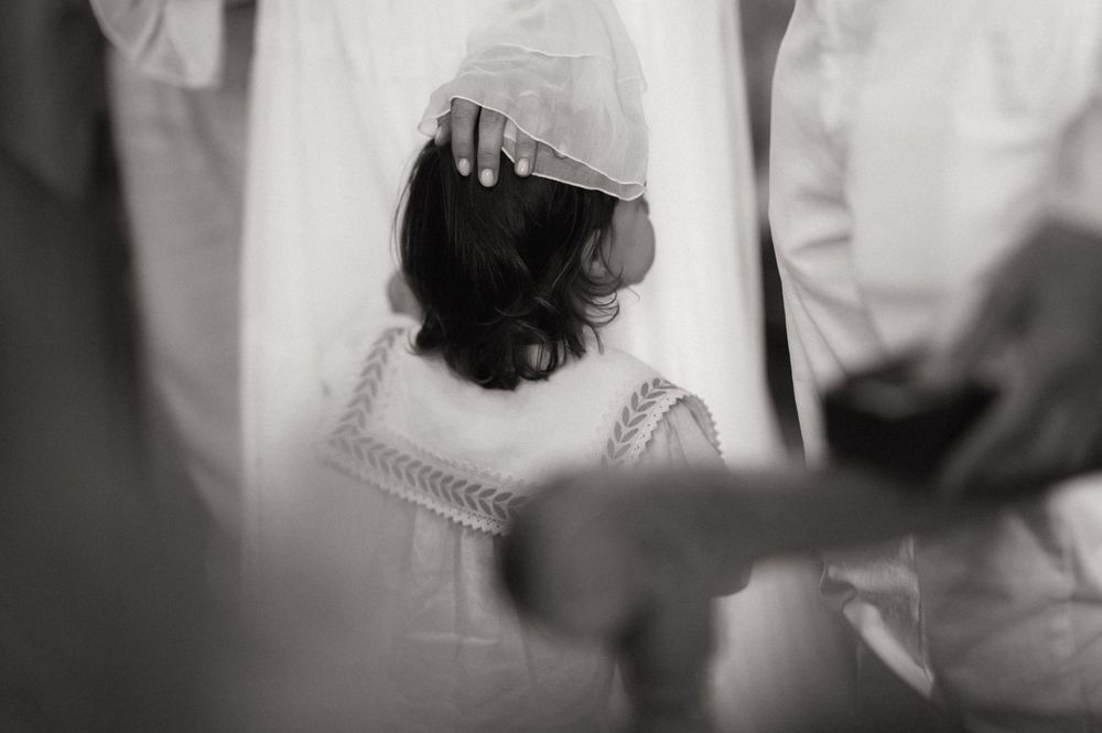 Black and white photo of a bride having her veil adjusted during wedding preparations.