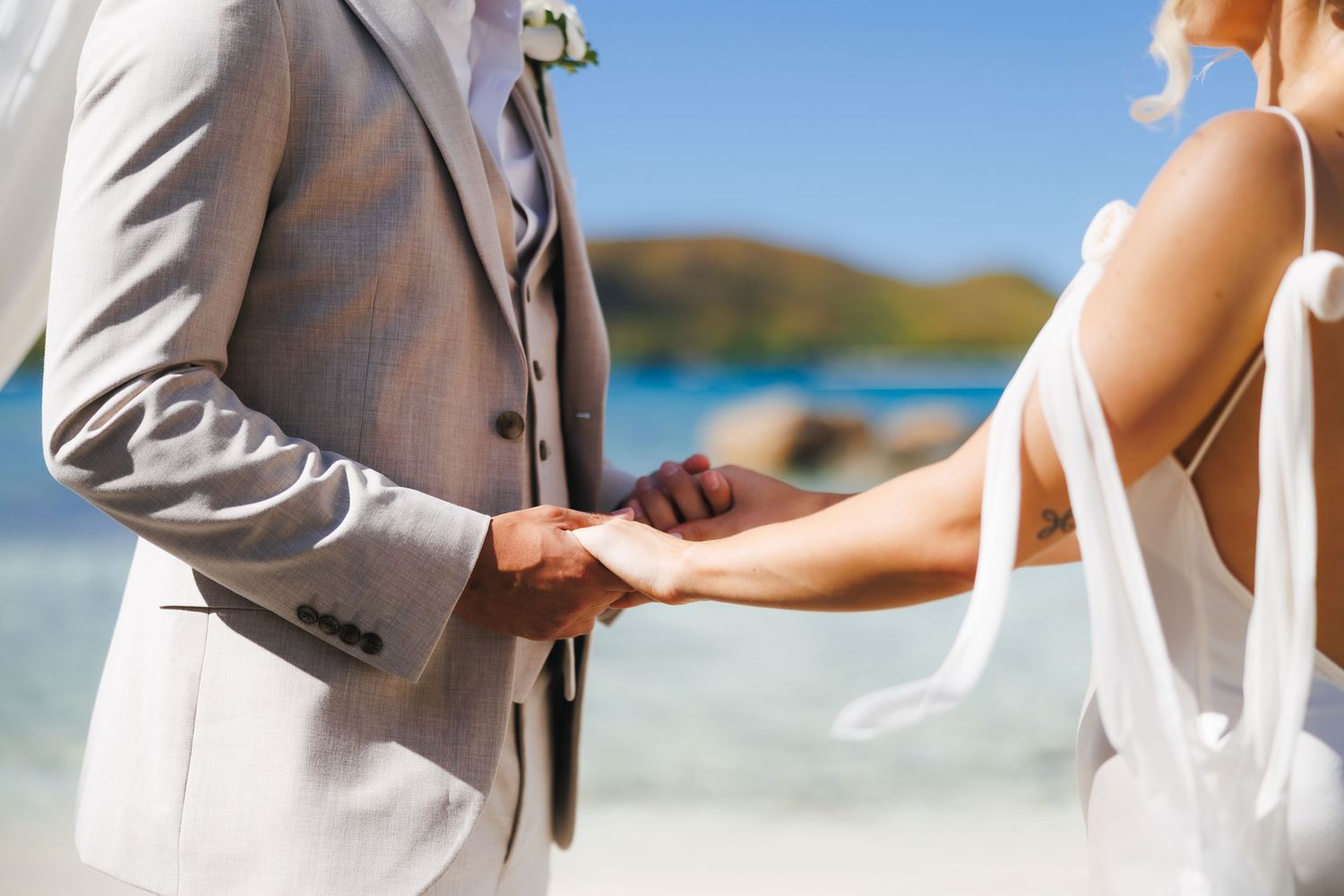 Bride and groom holding hands during their romantic beach wedding ceremony by the ocean.