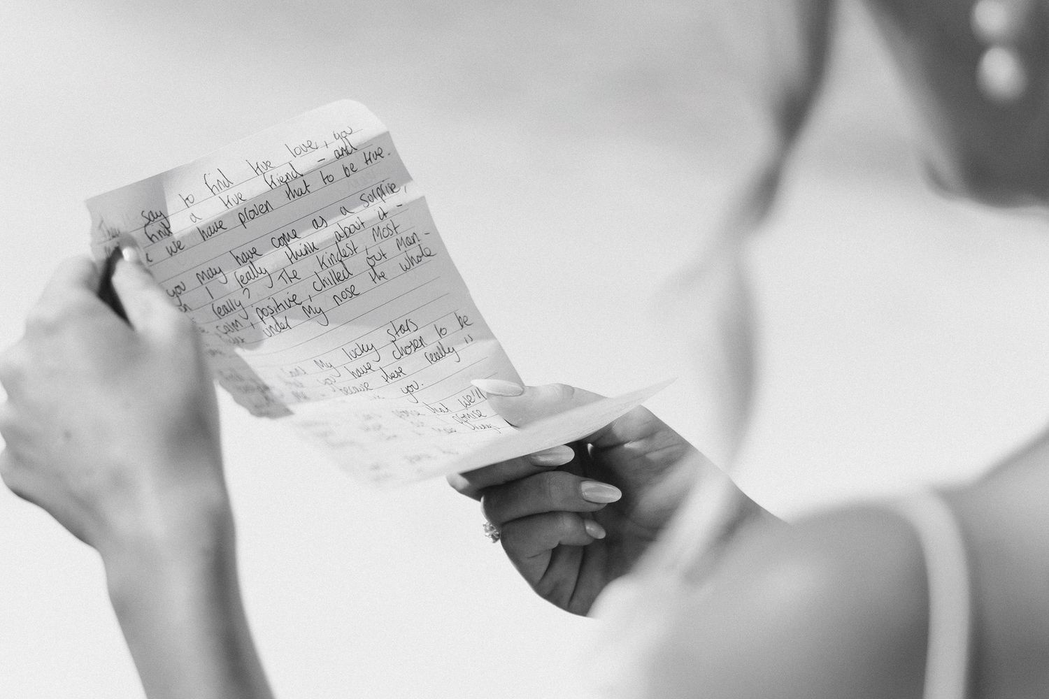 Black and white photo of a bride reading handwritten wedding vows on note cards.