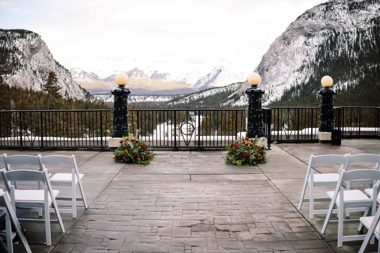 White chairs line the aisle on a Fairmont Banff Springs terrace overlooking a snowy river valley before a winter ceremony