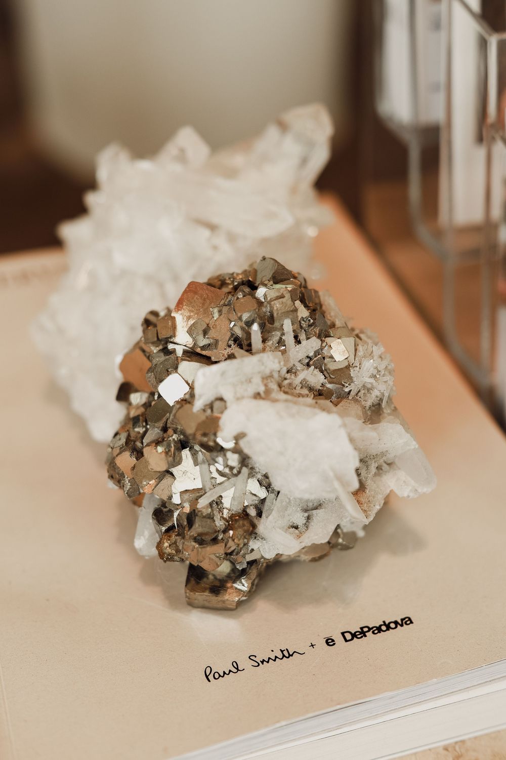 Pyrite and quartz crystal mineral specimen displayed on a Paul Smith x DePadova branded surface.