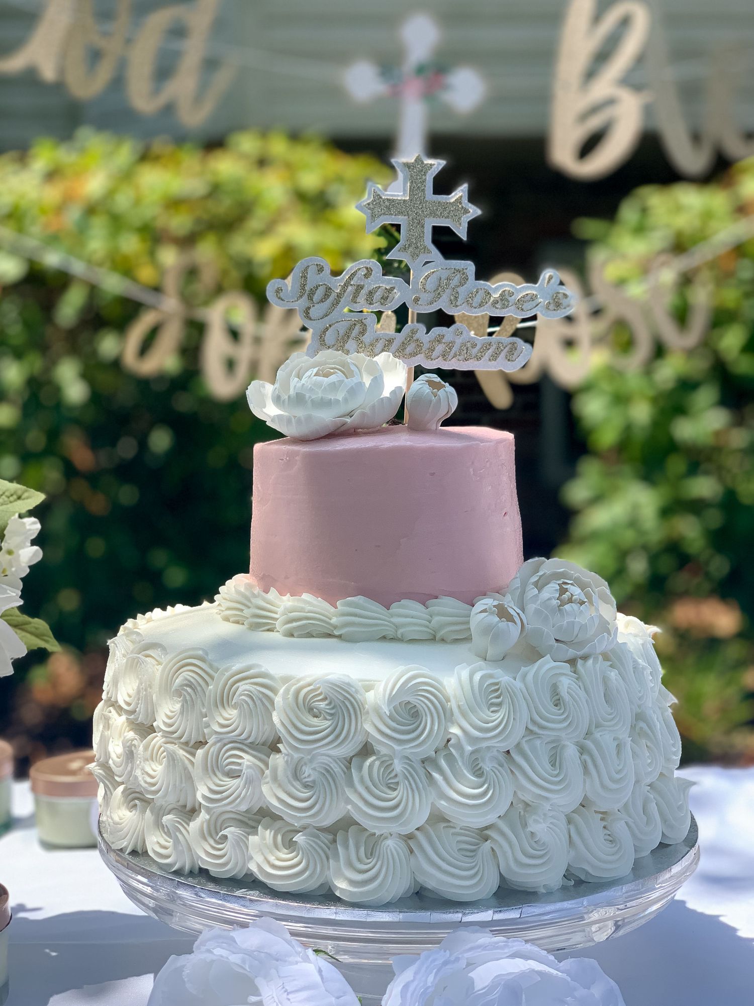 Pink baptism cake with a silver cross topper at a christening celebration in New Jersey