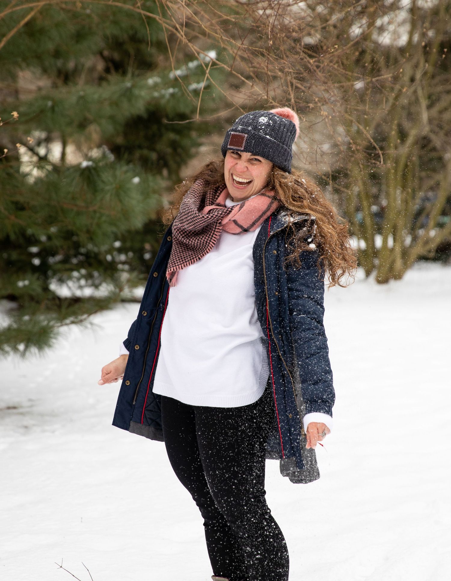 A joyful winter scene with someone wearing a knit hat and coat playing in the snow.