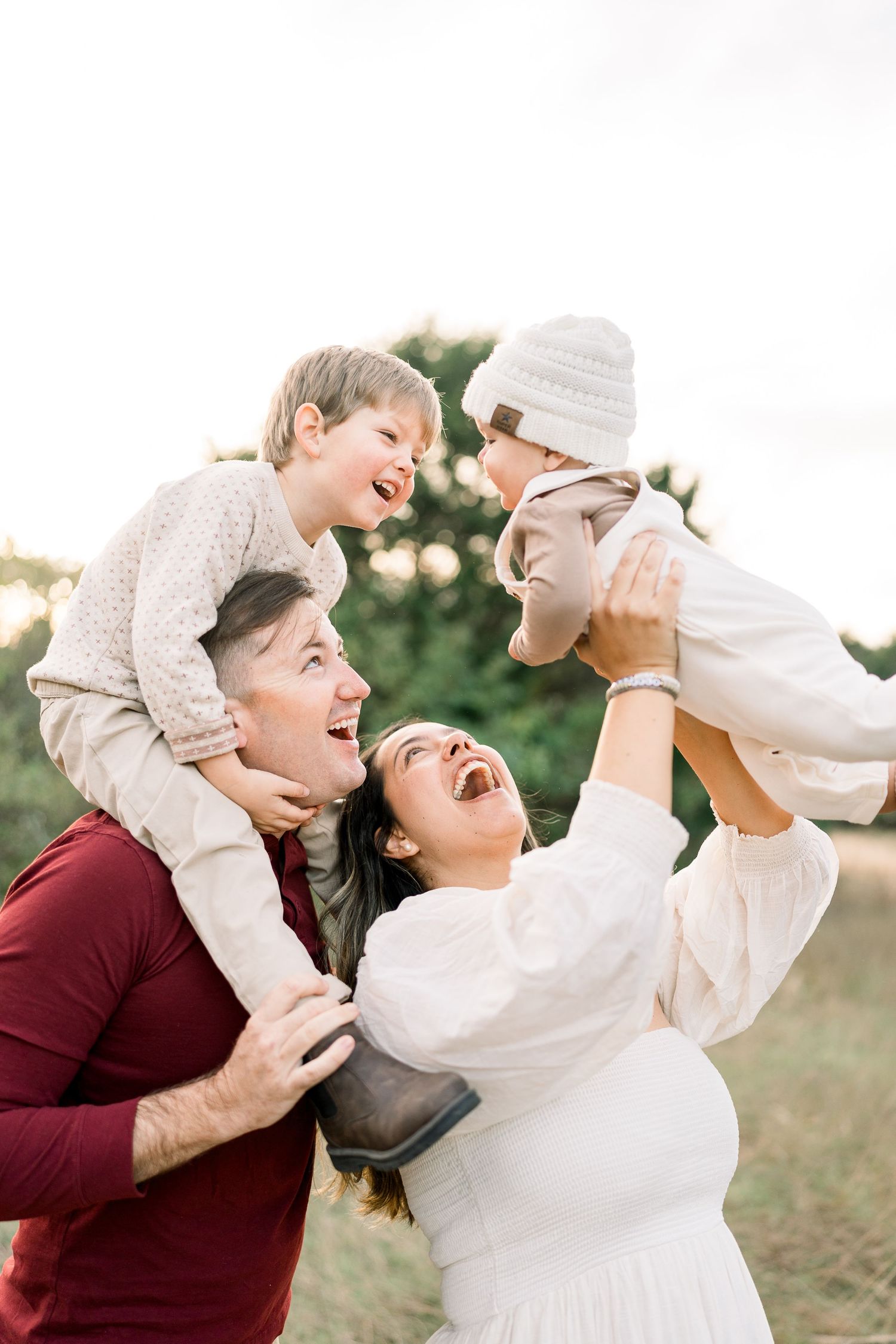 Joyful family playing and laughing together outdoors at sunset.