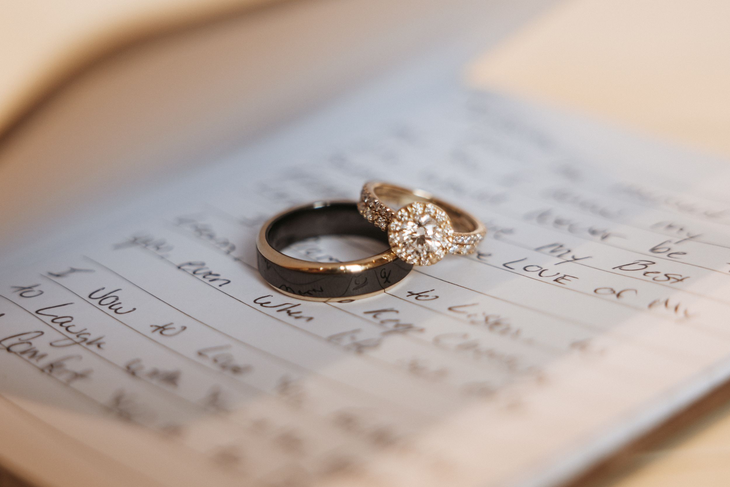 A diamond engagement ring rests on handwritten sheet music creating a romantic wedding detail shot.