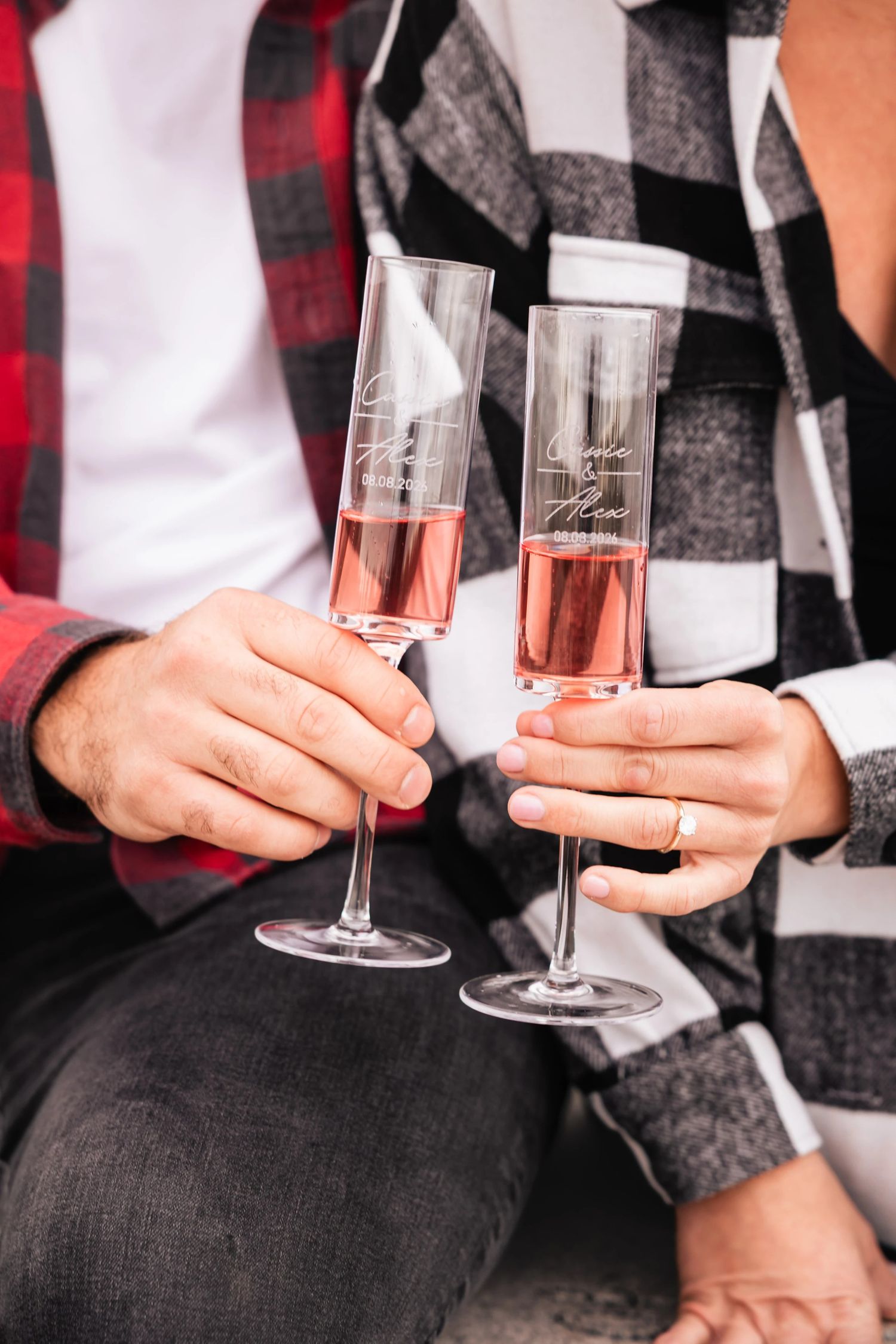 Two people toasting with champagne flutes filled with rosé, seated together in casual celebration. Engagement at Rockport Harbor, Rockport