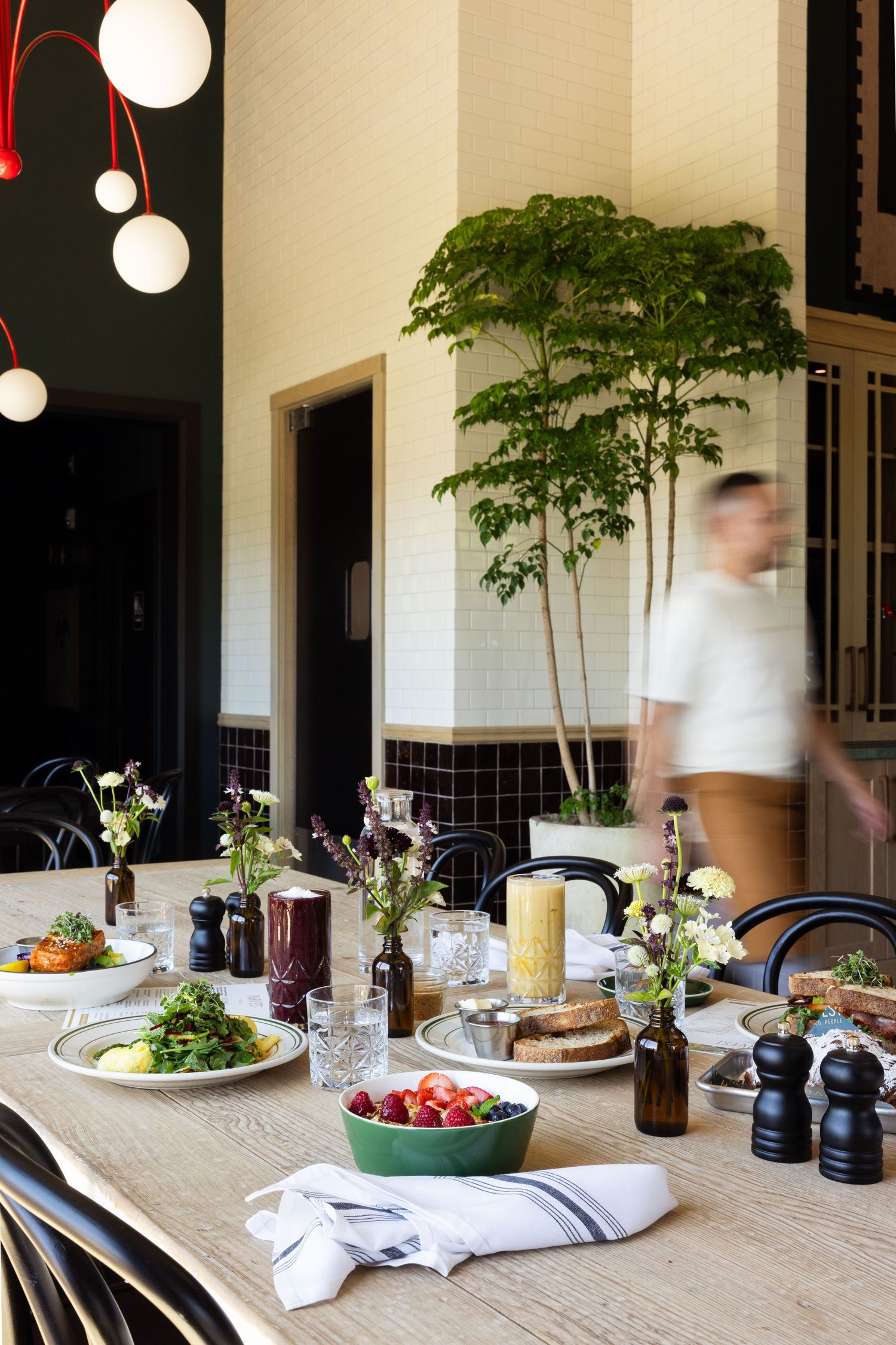 photo of restaurant table with delicious food with a server walking past, artistically blurred, in the background.