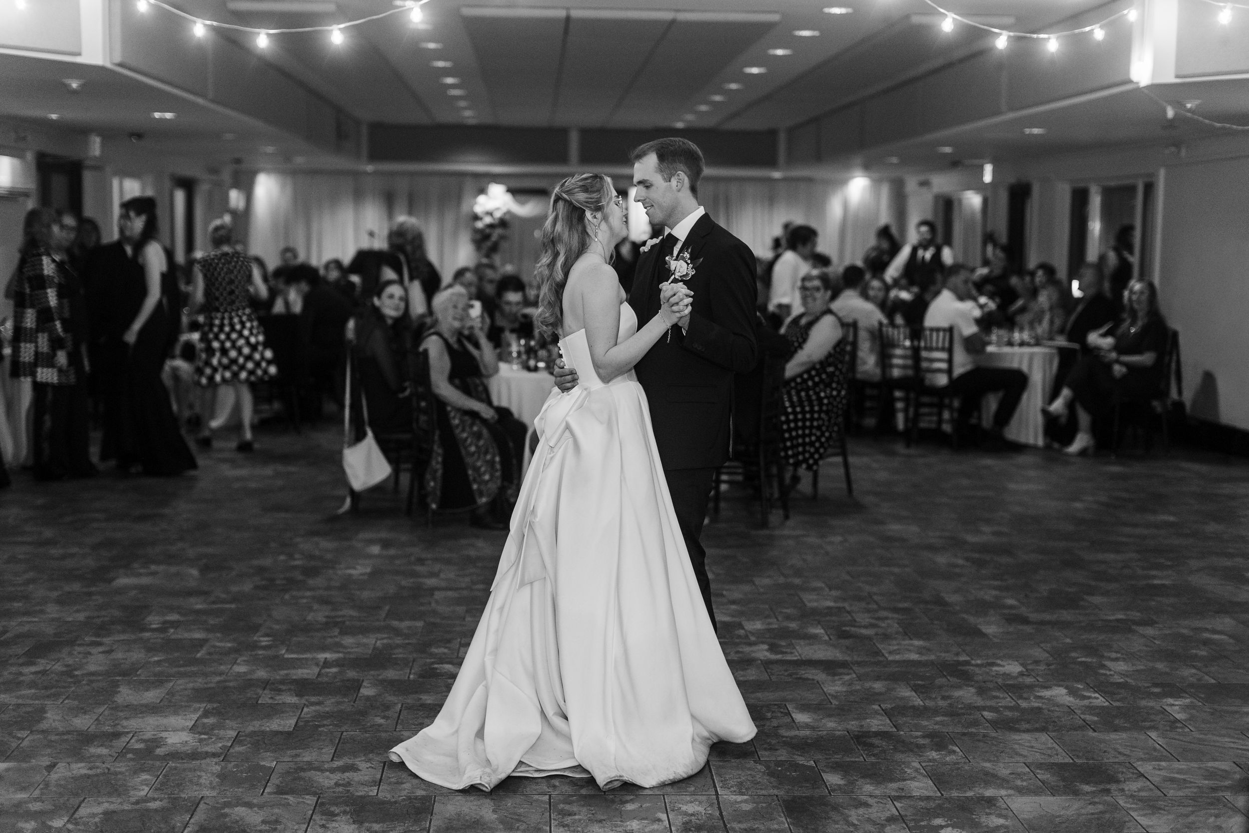 Black and white photo of bride and groom sharing their first dance at elegant wedding reception.