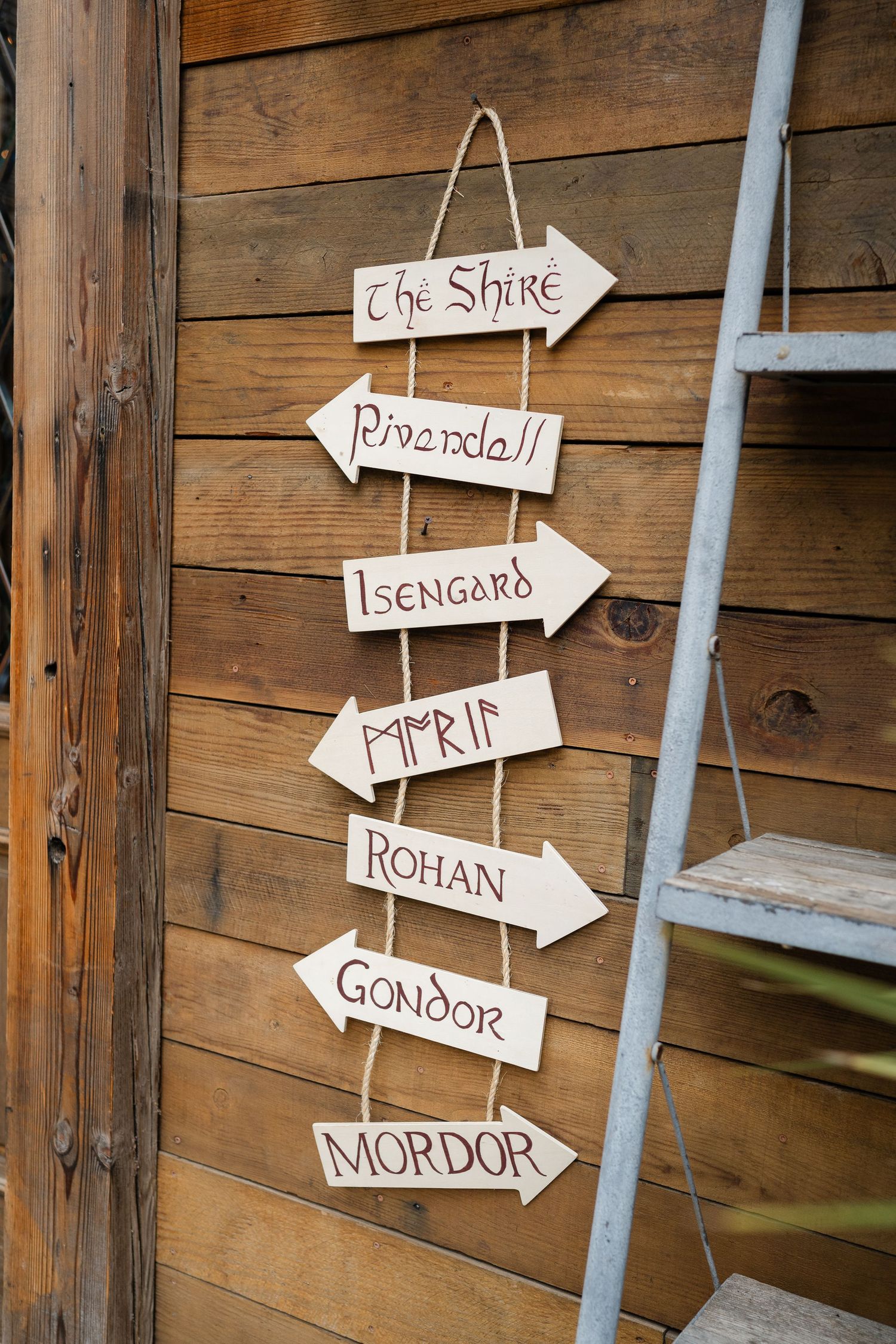Wooden directional signs listing Lord of the Rings locations including The Shire, Rivendell, Isengard, Rohan, Gondor, and Mordor.