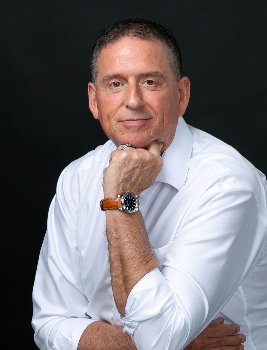 Man in a white shirt with his hand at his chin on a black backdrop, classic executive headshot