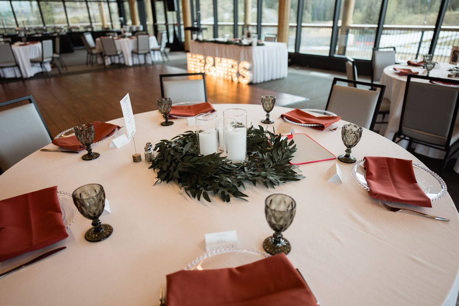 Reception table with white linens, terracotta napkins and candles at Vista Canmore