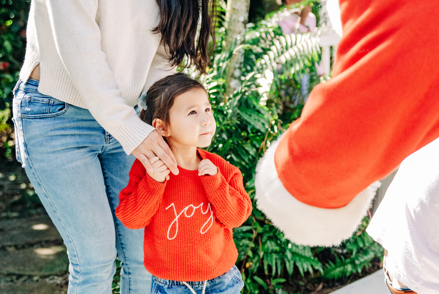 Lake Worth Beach Santa photos of a toddler meeting Santa Claus and reaching for his hand during a Christmas session.