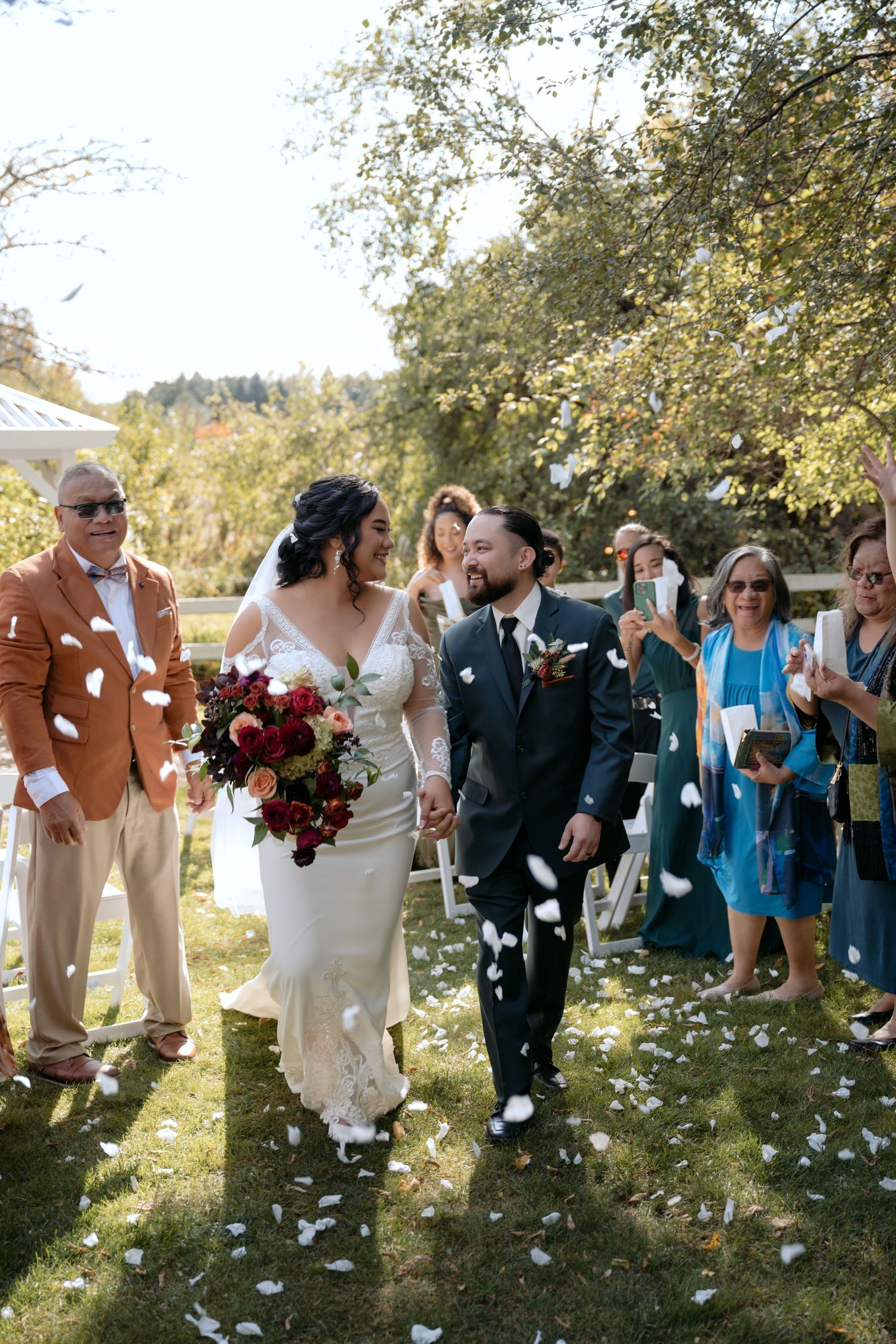 Hawaiian Bride and Groom walk down the aisle as family throws petals in the air after the ceremony at Trellis Weddings in Stillwater MN.