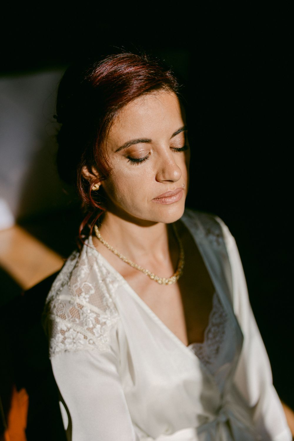 Ritratto della sposa con gli occhi chiusi nella luce della finestra.