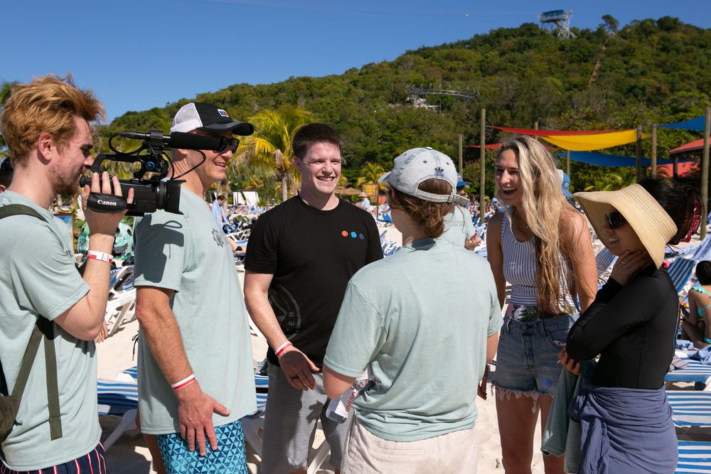 Group of young adults socializing and laughing together on a sunny beach resort.