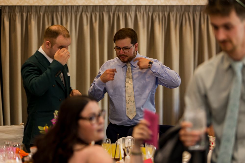 Men in formal attire adjusting ties at a wedding reception dinner event.
