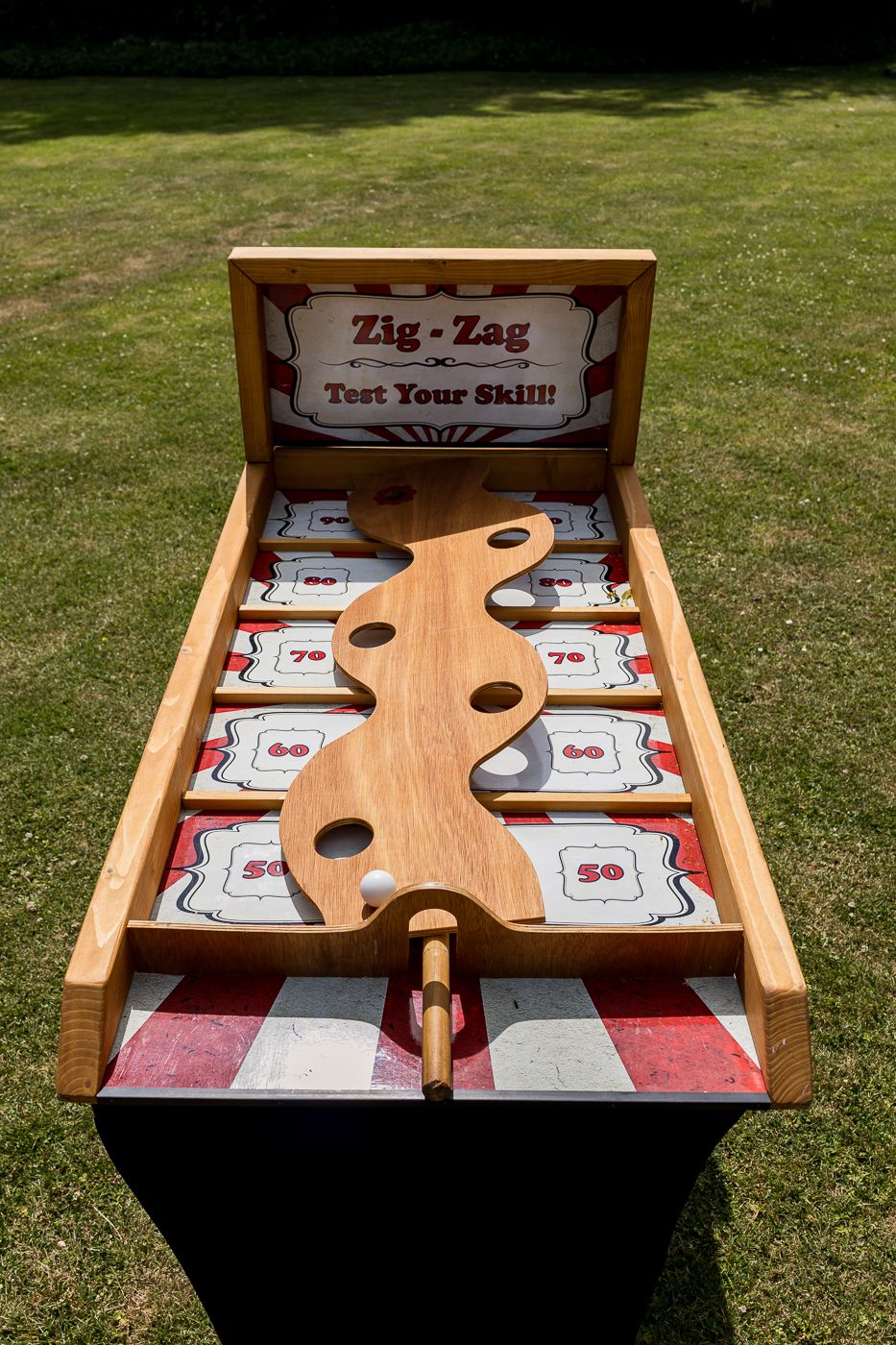 Wooden Zig-Zag carnival skill game with numbered scoring zones displayed outdoors on green grass.