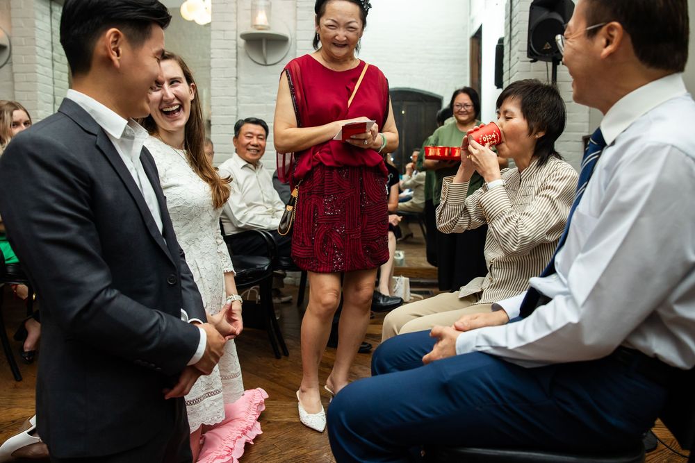 Joyful wedding guests laughing and celebrating indoors, with a woman in red dress and others sharing a fun moment.