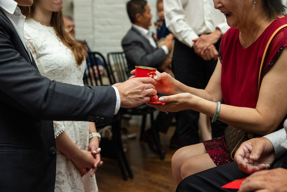 Guests exchanging red envelopes during a wedding ceremony, blending cultural traditions with modern celebration.