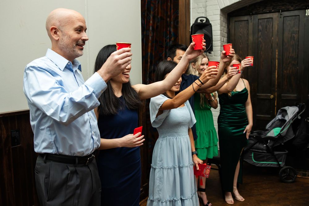 Group of people raising red cups in a toast at an indoor social gathering or party celebration.