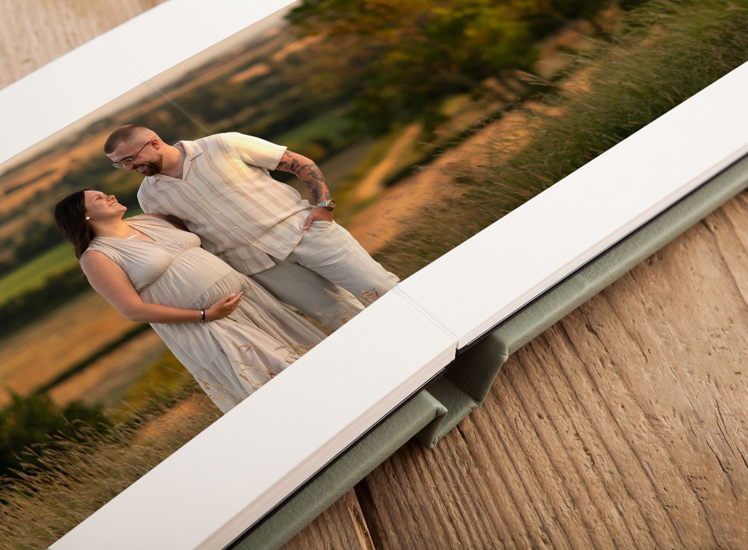 Couple in matching gray outfits sharing a romantic moment on a white bridge overlooking a scenic countryside.