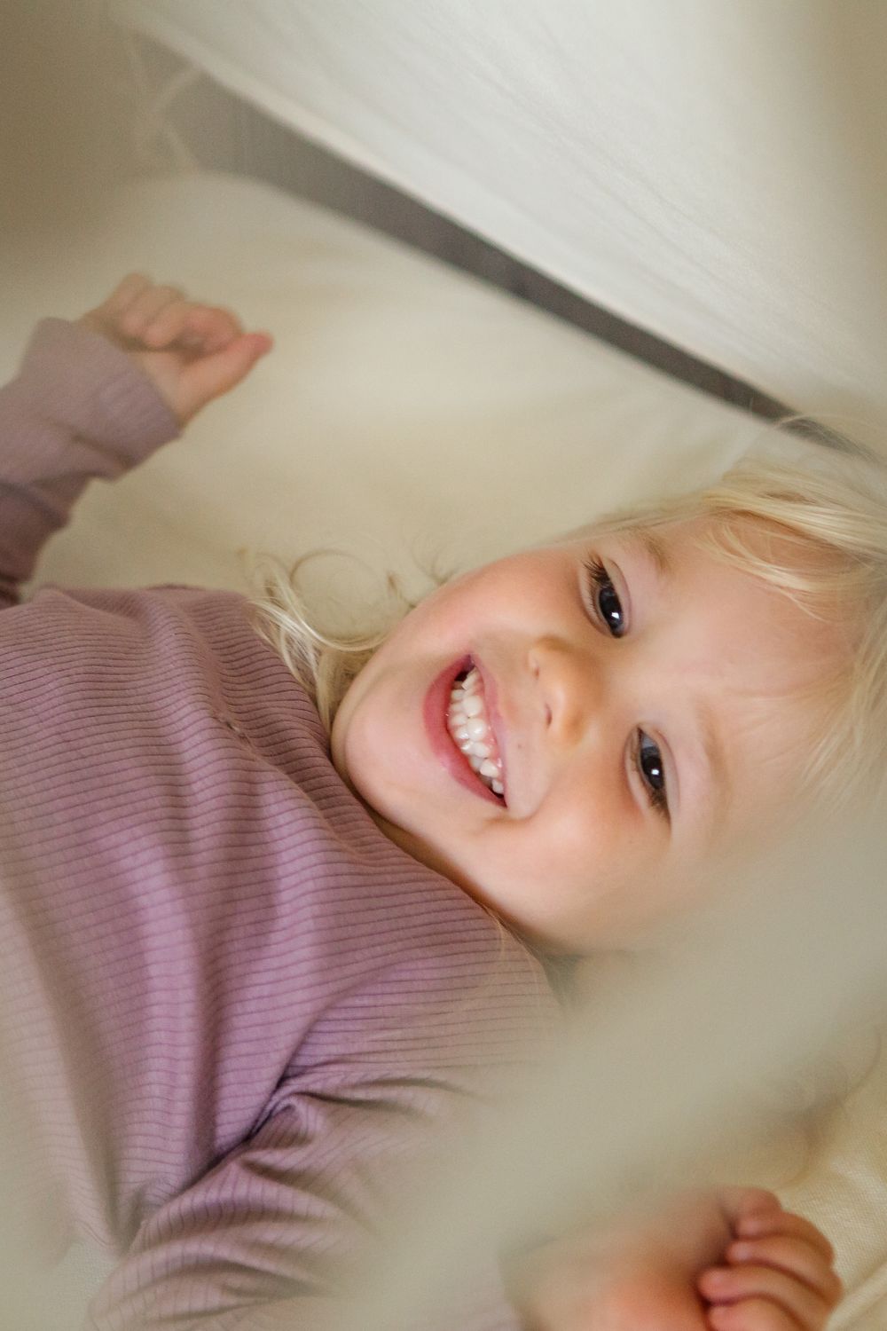 A series of four close-up photos showing a person in a purple sweater lying down with a joyful expression.