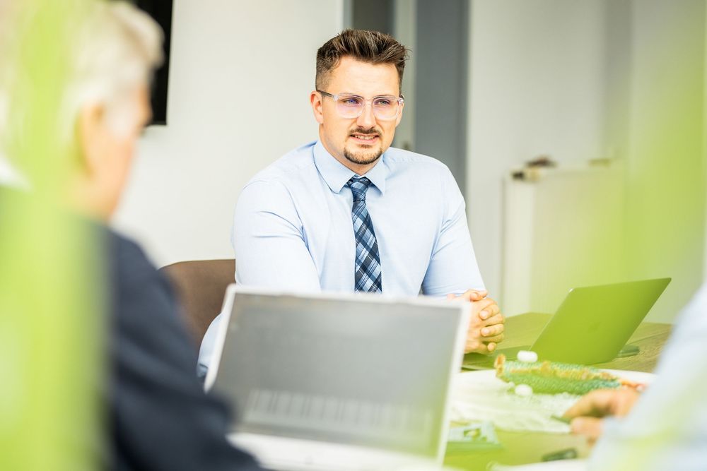 Professional businessman in blue shirt and tie attentively listening during a business meeting.